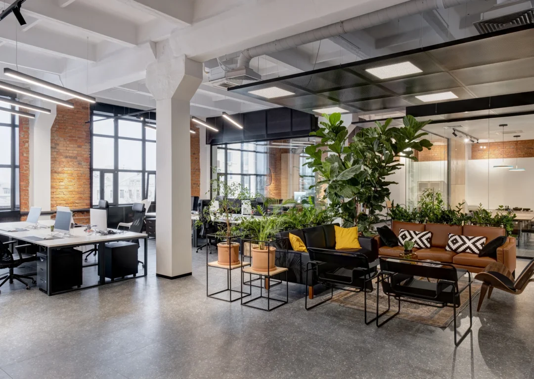 An open commercial property office space featuring abundant plants and modern furniture.