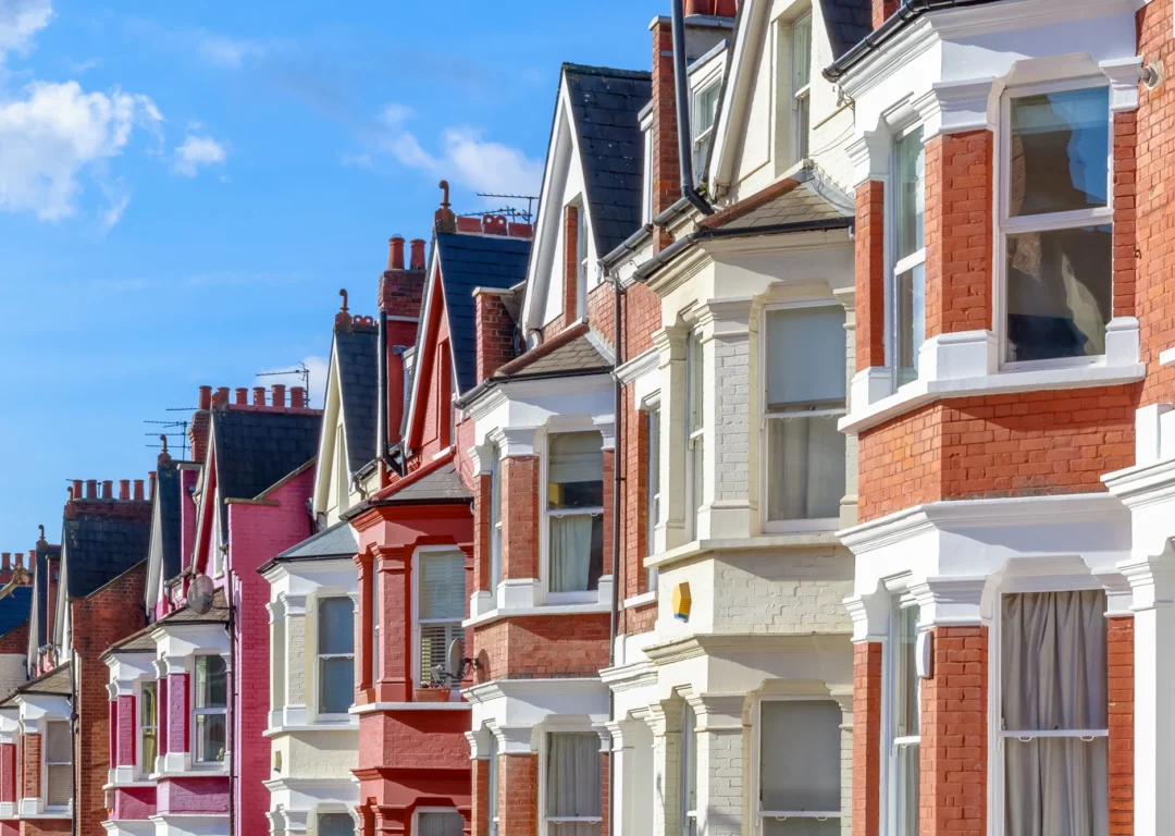A row of houses featuring white trim along their windows and doors, set against a clear blue sky.